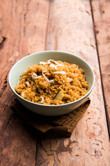 Wheat Laapsi/Lapsi/Shira/Halwa is an Indian sweet dish made of broken wheat or Daliya pieces and ghee along with nuts, raisins and dried fruits. It's a healthy food. served in a bowl, selective focus