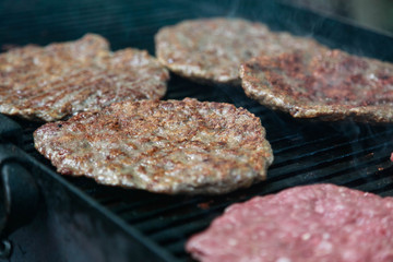 Grilling burgers and hot dogs on a huge grill outdoors.