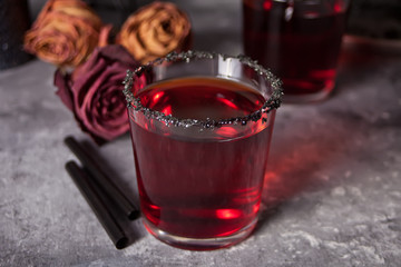 Two glasses with red cocktail, dried roses for Halloween party on the dark background