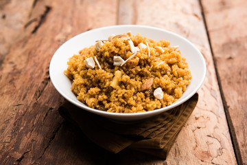 Wheat Laapsi/Lapsi/Shira/Halwa is an Indian sweet dish made of broken wheat or Daliya pieces and ghee along with nuts, raisins and dried fruits. It's a healthy food. served in a bowl, selective focus