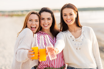 friendship and leisure concept - group of happy young women or female friends toasting non alcoholic drinks on summer beach