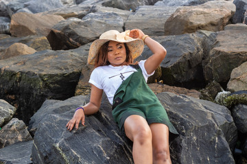 Young African lady laying on a pile of boulders by the beach