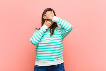 young pretty hispanic woman covering face with both hands saying no to the camera! refusing...