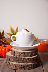 Cup of hot creamy cocoa with froth with autumn leaves and pumpkins on the background