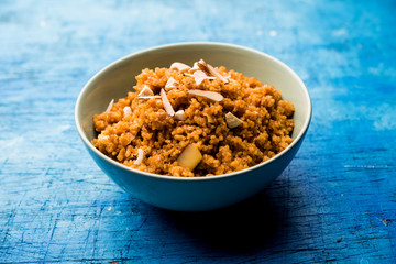 Wheat Laapsi/Lapsi/Shira/Halwa is an Indian sweet dish made of broken wheat or Daliya pieces and ghee along with nuts, raisins and dried fruits. It's a healthy food. served in a bowl, selective focus