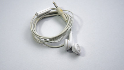 Close up view of a white tangled wired earphone on an isolated white background.