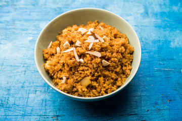 Wheat Laapsi/Lapsi/Shira/Halwa is an Indian sweet dish made of broken wheat or Daliya pieces and ghee along with nuts, raisins and dried fruits. It's a healthy food. served in a bowl, selective focus