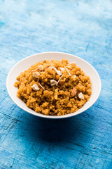 Wheat Laapsi/Lapsi/Shira/Halwa is an Indian sweet dish made of broken wheat or Daliya pieces and ghee along with nuts, raisins and dried fruits. It's a healthy food. served in a bowl, selective focus