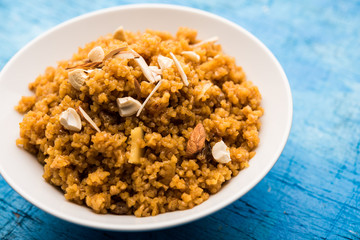 Wheat Laapsi/Lapsi/Shira/Halwa is an Indian sweet dish made of broken wheat or Daliya pieces and ghee along with nuts, raisins and dried fruits. It's a healthy food. served in a bowl, selective focus