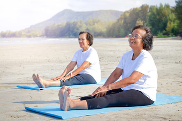 Two elderly women exercise on the beach, happy smile. The concept of the elderly community