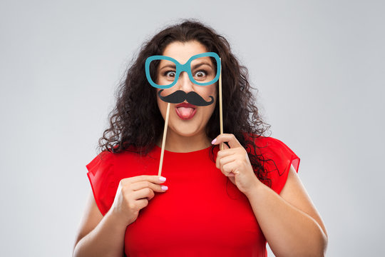 party props, photo booth and people concept - funny woman with big cartoon glasses and mustache showing tongue over grey background