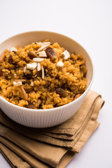 Wheat Laapsi/Lapsi/Shira/Halwa is an Indian sweet dish made of broken wheat or Daliya pieces and ghee along with nuts, raisins and dried fruits. It's a healthy food. served in a bowl, selective focus