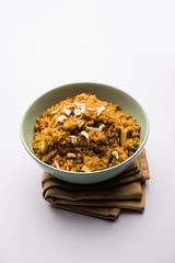 Wheat Laapsi/Lapsi/Shira/Halwa is an Indian sweet dish made of broken wheat or Daliya pieces and ghee along with nuts, raisins and dried fruits. It's a healthy food. served in a bowl, selective focus