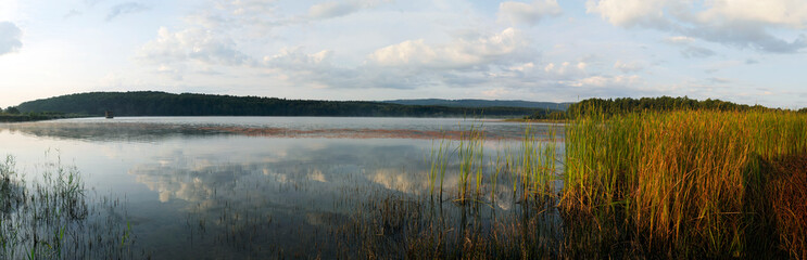 Beautiful panorama of autumn lake against the background of forest and sunny sky