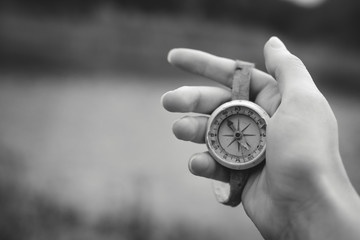 Woman hand holding a old compass with broken glass. Travel concept, path selection, navigation, tourism, hiking. Autumn background. crack on the glass as disappointment. black and white