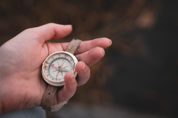 Woman hand holding a old compass with broken glass. Travel concept, path selection, navigation, tourism, hiking. Autumn background. crack on the glass as disappointment and cancellation of plans.