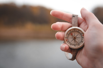 Woman hand holding a old compass with broken glass. Travel concept, path selection, navigation,...