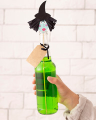 Close up of Halloween cute witch with green cocktail in bottle