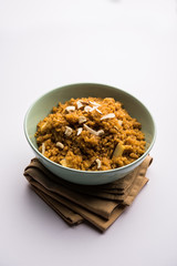 Wheat Laapsi/Lapsi/Shira/Halwa is an Indian sweet dish made of broken wheat or Daliya pieces and ghee along with nuts, raisins and dried fruits. It's a healthy food. served in a bowl, selective focus