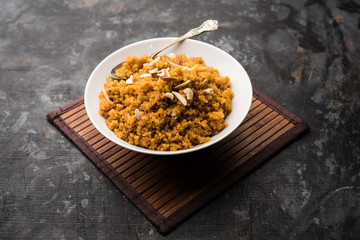 Wheat Laapsi/Lapsi/Shira/Halwa is an Indian sweet dish made of broken wheat or Daliya pieces and ghee along with nuts, raisins and dried fruits. It's a healthy food. served in a bowl, selective focus