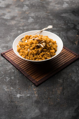 Wheat Laapsi/Lapsi/Shira/Halwa is an Indian sweet dish made of broken wheat or Daliya pieces and ghee along with nuts, raisins and dried fruits. It's a healthy food. served in a bowl, selective focus