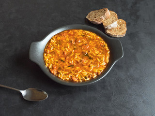 Delicious Italian sausage soup with orzo on black background. Top view. 
