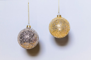 Two Christmas balls hanging on a color background