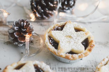 Mince pie on wooden table and decorative pine cones and Christmas lights. New Year and Christmas...