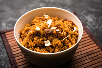 Wheat Laapsi/Lapsi/Shira/Halwa is an Indian sweet dish made of broken wheat or Daliya pieces and ghee along with nuts, raisins and dried fruits. It's a healthy food. served in a bowl, selective focus