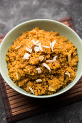 Wheat Laapsi/Lapsi/Shira/Halwa is an Indian sweet dish made of broken wheat or Daliya pieces and ghee along with nuts, raisins and dried fruits. It's a healthy food. served in a bowl, selective focus