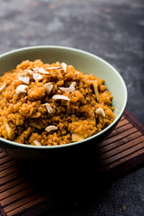 Wheat Laapsi/Lapsi/Shira/Halwa is an Indian sweet dish made of broken wheat or Daliya pieces and ghee along with nuts, raisins and dried fruits. It's a healthy food. served in a bowl, selective focus