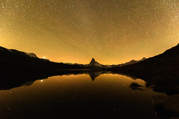 Incredible night view of Stellisee lake with Matterhorn Cervino peak in Swiss Alps. Millions of stars in the pre-bright sky. Zermatt resort location, Switzerland. Landscape astrophotography
