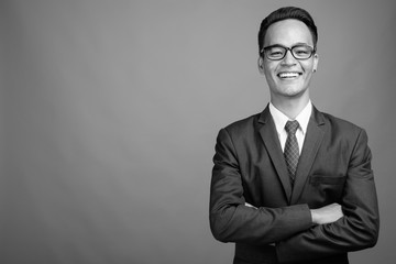 Young handsome Indian businessman against gray background