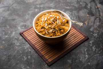 Wheat Laapsi/Lapsi/Shira/Halwa is an Indian sweet dish made of broken wheat or Daliya pieces and ghee along with nuts, raisins and dried fruits. It's a healthy food. served in a bowl, selective focus