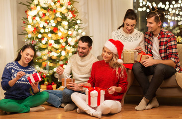 celebration and holidays concept - happy friends with glasses celebrating christmas at home party and opening presents