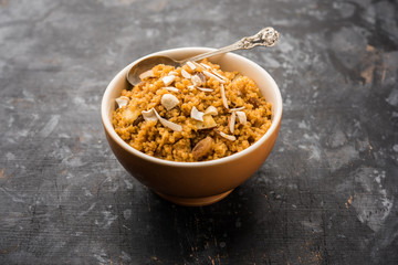 Wheat Laapsi/Lapsi/Shira/Halwa is an Indian sweet dish made of broken wheat or Daliya pieces and ghee along with nuts, raisins and dried fruits. It's a healthy food. served in a bowl, selective focus