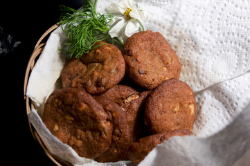 A wicker basket lined with white paper towels holding fresh baked homemade peanut butter cookies with peanuts and chocolate chips.