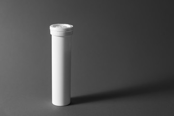 Round white tube with a lid for effervescent tablets, vitamins. New cupboard for storing drugs. Black and white photo. copy space. The concept of health, the treatment of viral diseases and headache