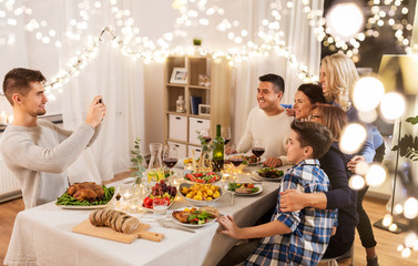 celebration, holidays and people concept - happy family having dinner party at home and taking selfie by smartphone