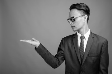 Young handsome Indian businessman against gray background