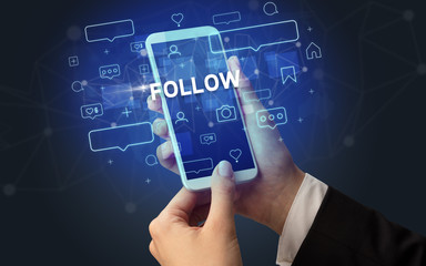 Female hand typing on smartphone with FOLLOW inscription, social media concept