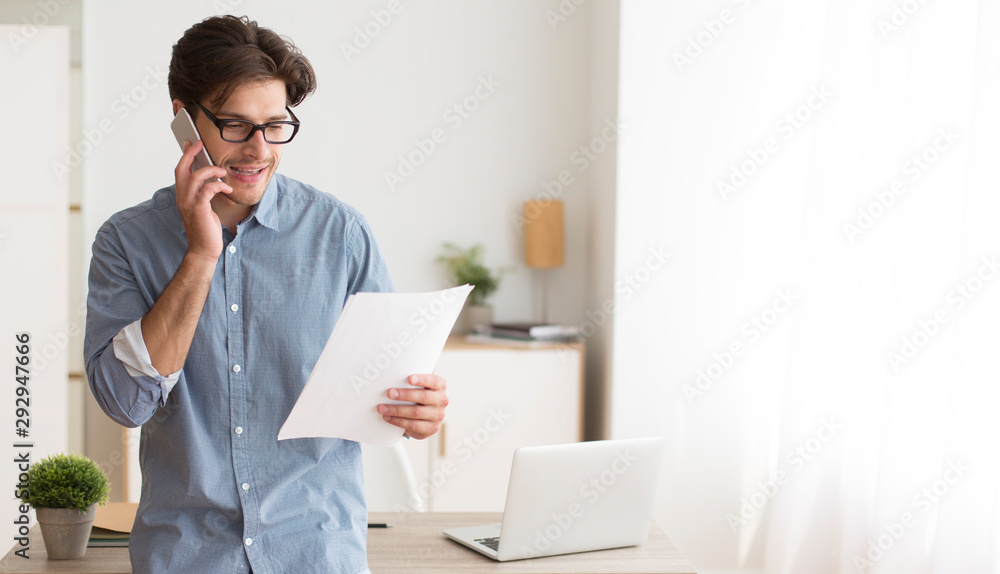 Poster man talking on cellphone holding paper notification in office