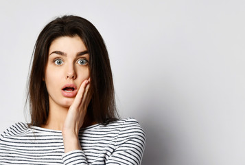 Surprised happy beautiful woman looking straight into the camera with excitement isolated on bright background