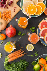 food , healthy eating and vegetarian concept - mason jar glasses of orange and carrot juices with paper straws, fruits and vegetables on slate table