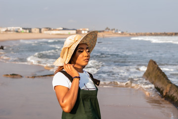 Young African lady in a sun hat by the beach