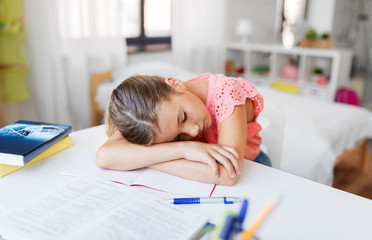 children, education and learning concept - tired student girl sleeping on table at home