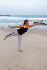 Woman doing a yoga pose by the beach