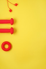 Top view of dumbbell, headphones, carpal expander, apple on a yellow background with space for text. Creative flat lay sport and fitness concept.