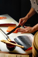 Closeup of chef hands preparing japanese food. Japanese chef making sushi at restaurant. Young chef...