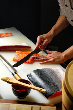 Closeup of chef hands preparing japanese food. Japanese chef making sushi at restaurant. Young chef making  traditional japanese sushi on cuting board . with copyspace .
